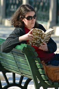 Woman sitting on park bench, reading book